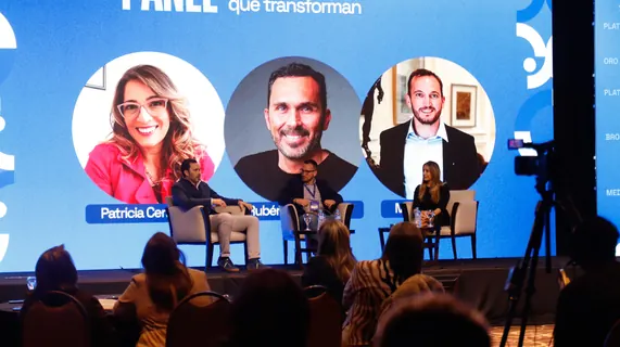 Oradores en panel con la pantalla de presentación del 6.º Encuentro